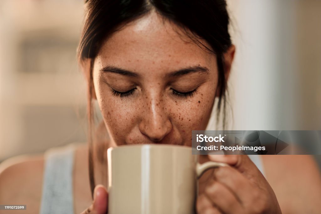 A good day starts with good coffee Shot of a young woman enjoying a cup of coffee at home Coffee - Drink Stock Photo