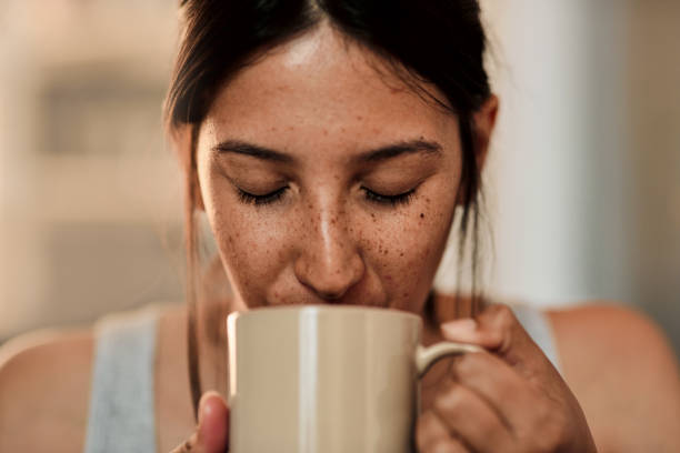 A good day starts with good coffee Shot of a young woman enjoying a cup of coffee at home coffee break photos stock pictures, royalty-free photos & images
