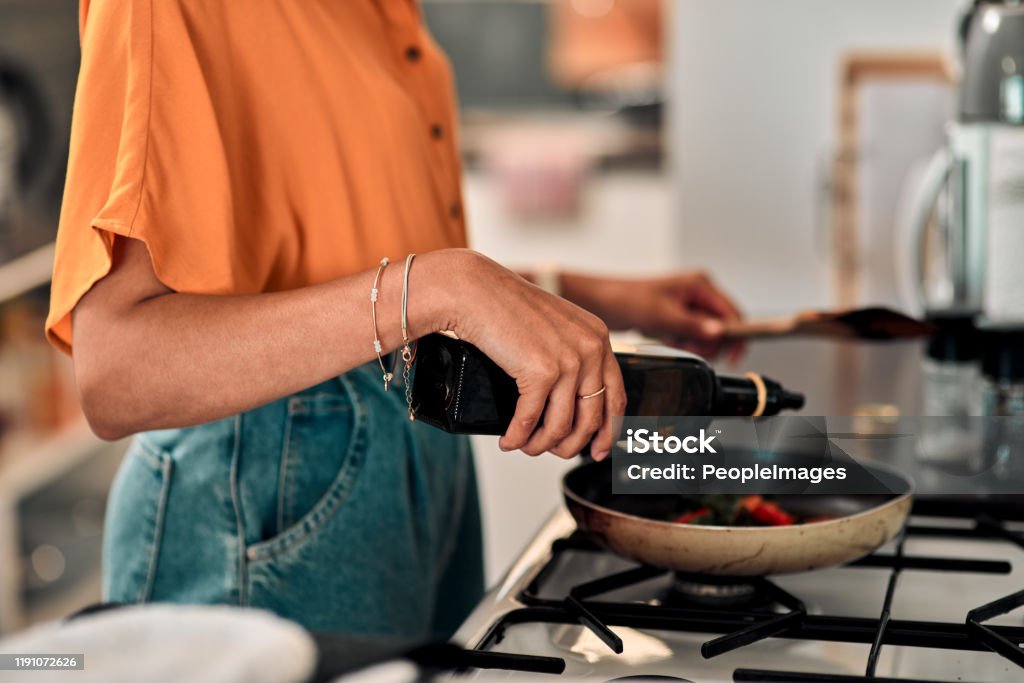 Make the switch to healthy oil Cropped shot of a young woman preparing a healthy meal at home Cooking Stock Photo