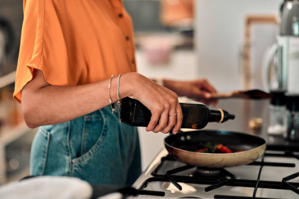 Make the switch to healthy oil Cropped shot of a young woman preparing a healthy meal at home atkins diet stock pictures, royalty-free photos & images