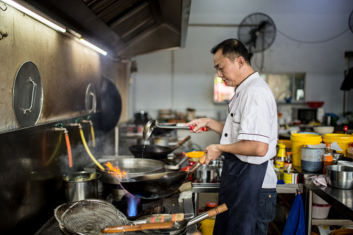 An Asian Chinese chief is cooking in the kitchen