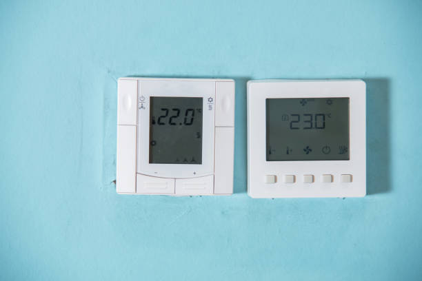 un thermostat programmable honeywell pour contrôler le climatiseur et le chauffage dans une maison. unité de commande du système de climatisation sur le mur. commutateur de prise de thermostat blanc isolé sur un fond gris. - control panel power switch video game photos et images de collection