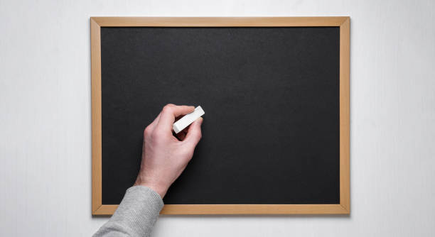 istock Male hand with chalk on the empty blackboard or chalkboard. 1191079563