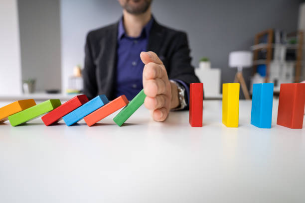 istock Male Hand Stopping The Domino From Falling 1191080362