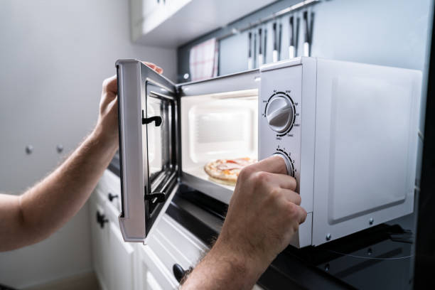 istock Hand Baking Pizza In Microwave Oven 1191081119