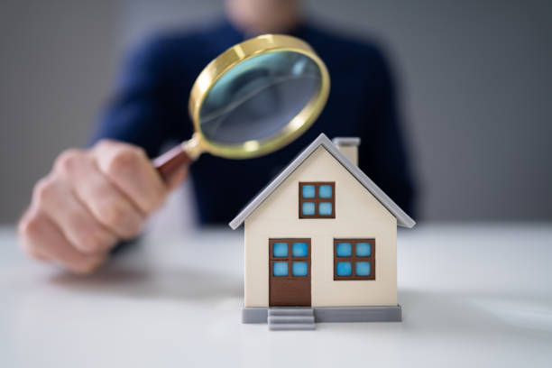 istock Person Hands With Magnifying Glass And Model House 1191081794