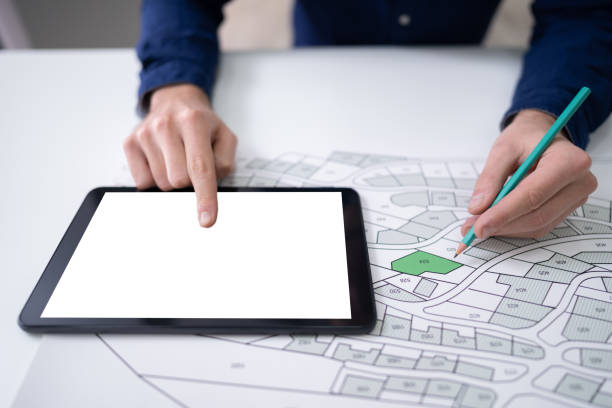 istock Human Hand Holding Pencil Over Cadastre Map 1191081806