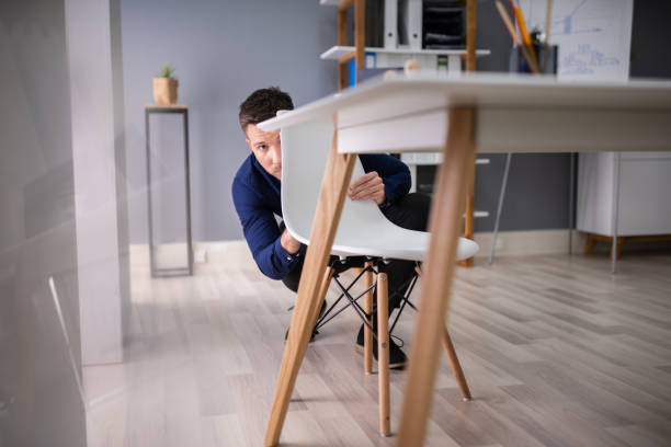 afraid businessman peeking behind chair - hiding fear men peeking fotografías e imágenes de stock