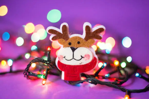 Reindeer Christmas decoration is placed among Christmas led lights. Beautiful multicolored bokeh is visible in the background.