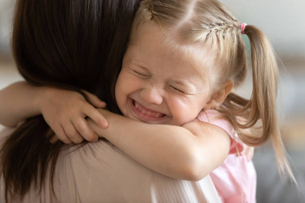 Funny cute little girl smiling embracing foster care parent mum Funny little child girl smiling embrace foster care parent mum, adorable sweet small kid adopted daughter cute face hug mother caretaker holding tight feel happy express love get new family concept orphan stock pictures, royalty-free photos & images