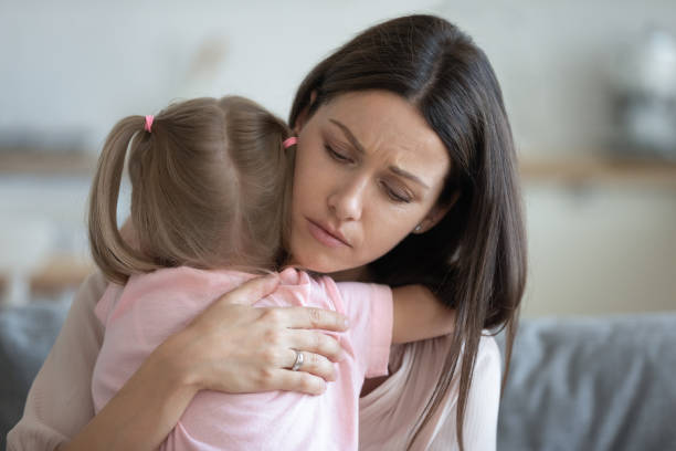 jeune mère adoptive inquiète réconfortant embrassant la fille adoptive d'enfant - maman anxieuse photos et images de collection