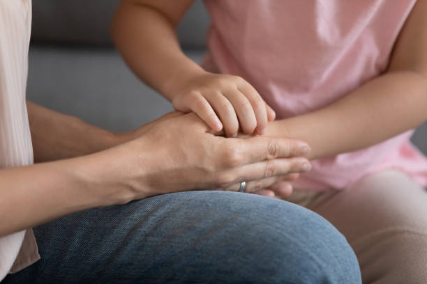 primo piano della figlia bambina che tiene le mani della madre affidatare adulta - multi generation family adoption family human hand foto e immagini stock