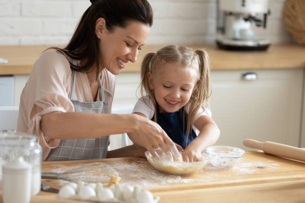 istock Cute child daughter helping mum kneading dough together in kitchen 1191083814