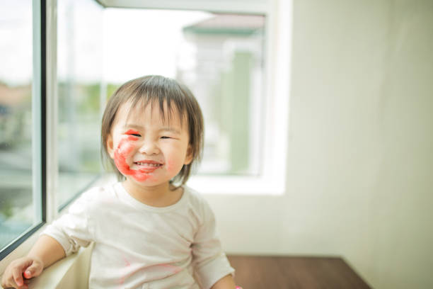 An Asian Chinese cute little girl paiting her on face.