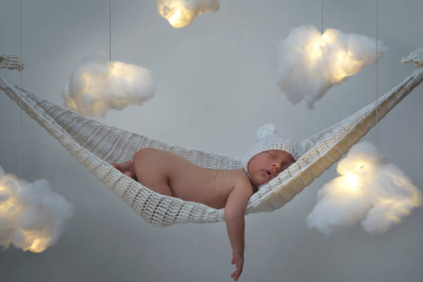 Cute little baby sleeping in the hammock Cute little baby sleeping in the hammock with a lot clouds made of cotton wool bear stomach stock pictures, royalty-free photos & images