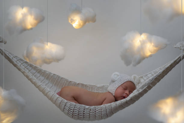 Cute little baby sleeping in the hammock Cute little baby sleeping in the hammock with a lot clouds made of cotton wool bear stomach stock pictures, royalty-free photos & images