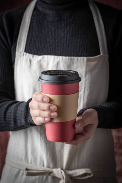 istock female with apron serving coffee with disposable paper cup 1191087734