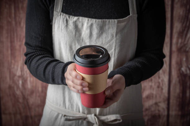 istock female with apron serving coffee with disposable paper cup 1191088266