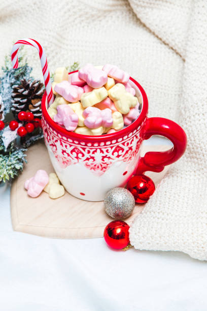 istock Red mug with marshmallows and winter ornaments on a white sheets 1191089962