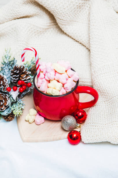 istock Red mug with marshmallows and winter ornaments on a white sheets 1191090280