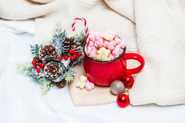 istock Red mug with marshmallows and winter ornaments on a white sheets 1191090526