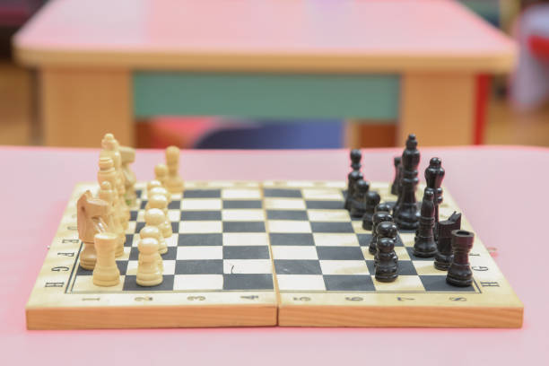 drewniane szachy na szachownicy. gra intelektualna . drewniane szachy i zegar szachowy na różowym tle. - chess board room business strategy zdjęcia i obrazy z banku zdjęć