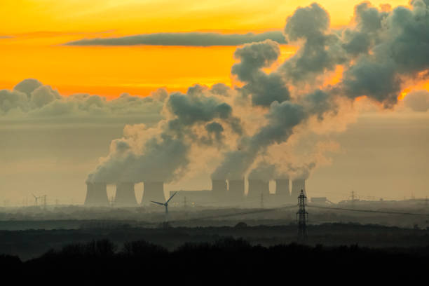 les imposantes tours de refroidissement d'une centrale électrique près de drax dans le yorkshire du nord, royaume-uni, avec des panaches de vapeur d'eau frapper l'air froid de la nuit en hiver. - industry dusk night sustainable resources photos et images de collection