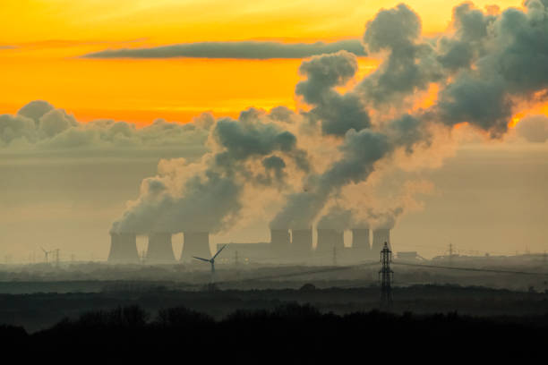 The imposing cooling towers of a Power Station near Drax in North Yorkshire, UK, with plumes of water vapour hitting the cold night air in Winter. stock photo