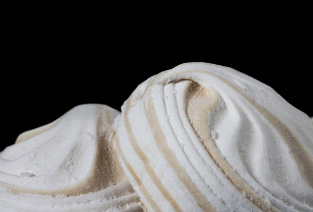 istock Close-up, macro, on two airy white marshmallows close-up on a black background. Cooking and sweets recipe 1191092848