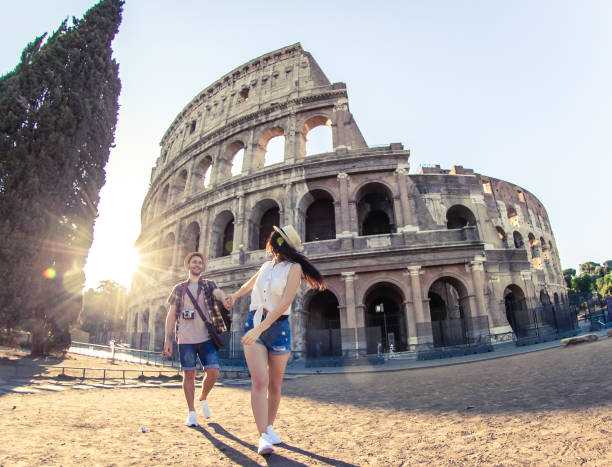 jeune couples heureux de la marche de touriste retenant des mains au colisée. viens avec moi. rome, italie - coliseum rome italy city photos et images de collection