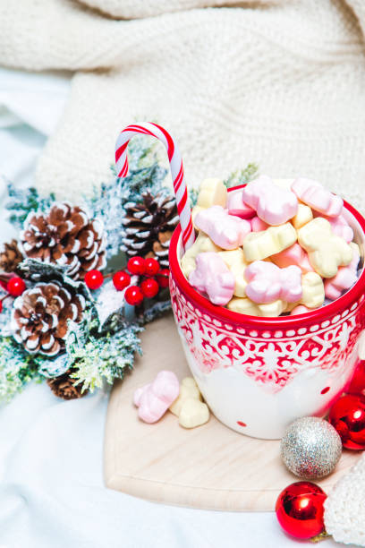 istock Red mug with marshmallows and winter ornaments on a white sheets 1191102393