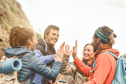 Grupo de amigos apilando las manos mientras hacen excursión de trekking en la montaña - Jóvenes turistas divirtiéndose explorando la naturaleza salvaje - Trekker, equipo, caminata y personas de viaje concepto photo