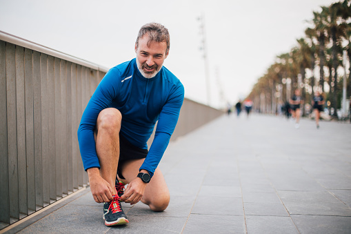 Mature man tying shoelace and preparing for running.