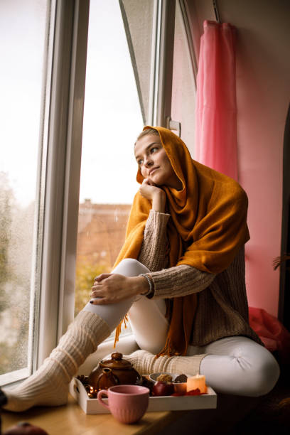 istock Young woman reminiscing on old memories while looking through the window 1191111358
