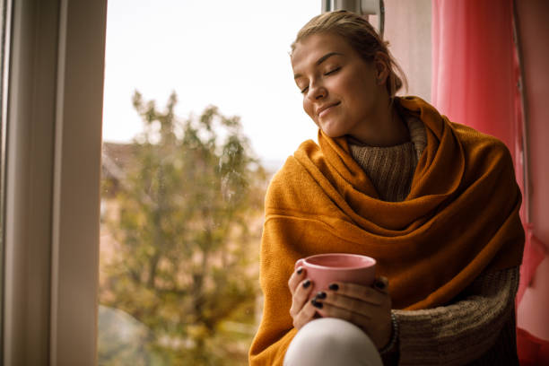 Photo of Smiling young woman enjoying a warm cup of tea on a cold autumn day