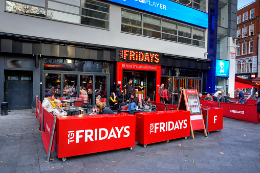 London, United Kingdom - September 7, 2019: Exterior of TGI Fridays in Leceister Square in London UK with motion blurred pedestrians and diners seated outside