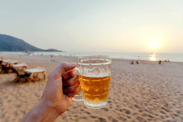 istock Sunset with beer in a hand. Vacation on a calm sunny beach 1191114873