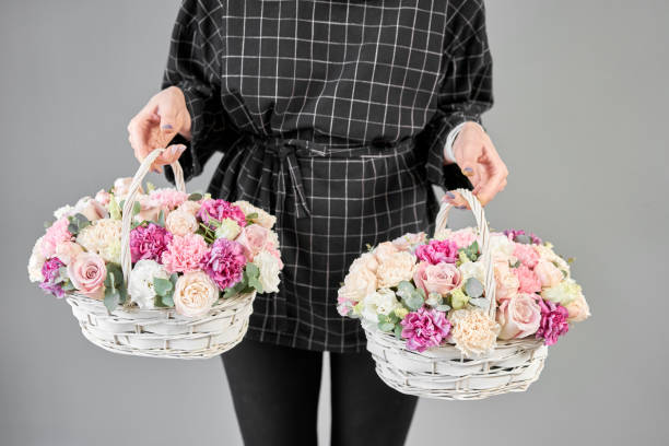 dos arreglos de flores en cesta de mimbre. moderna tienda de flores. terminado el trabajo de la floristería. bonito ramo de flores mezcladas en manos de las mujeres. entrega de flores recién cortadas de la tienda en línea - wicker basket store gift shop fotografías e imágenes de stock