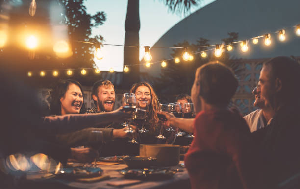 felice cena in famiglia e degustazione di bicchieri di vino rosso in cena barbecue - persone con diverse età ed etnia che si divertono insieme - genitori giovani e anziani e concetto di attività del fine settimana gastronomico - family dinner eating meal foto e immagini stock