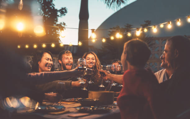 バーベキューディナーパーティーで幸せな家族の食事と赤ワイングラスを味わう - 異なる年齢と民族を持つ人々は一緒に楽しんで - 若者と高齢の両親と食品の週末の活動のコンセプト - スペイン 写真 ストックフォトと画像