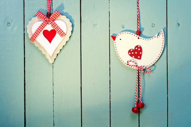 Ornate handmade Valentine decorations (bird and heart) on a wooden painted background. Space for copy.