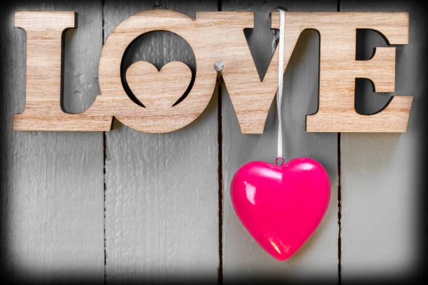 Valentine decoration (LOVE sign and a red heart) on a wooden painted background. Vignette, space for copy.