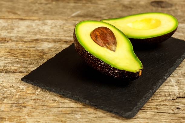 istock avocado on a dark wood background. tinting. selective focus. Slate plate with avocado. 1191123225