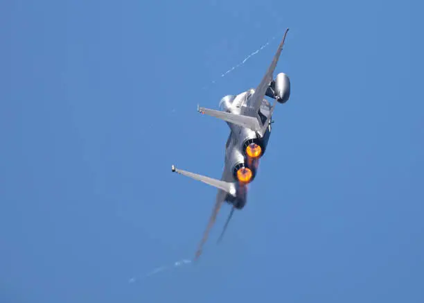 Very close tail view of a F15 Eagle in a high G turn, with condensation streaks at the wing tips, with afterburner on