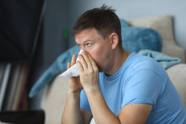 istock Man blowing his nose in a napkin while sitting 1191133207