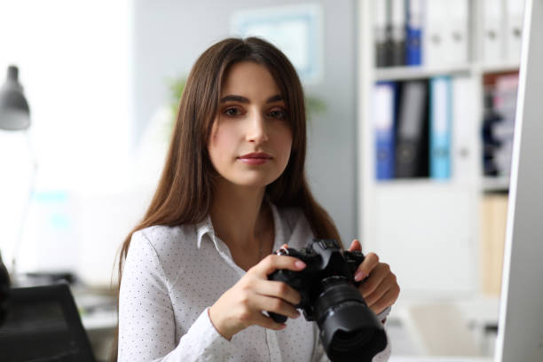 istock Woman sitting at worktable watching photosession at camera display 1191133255