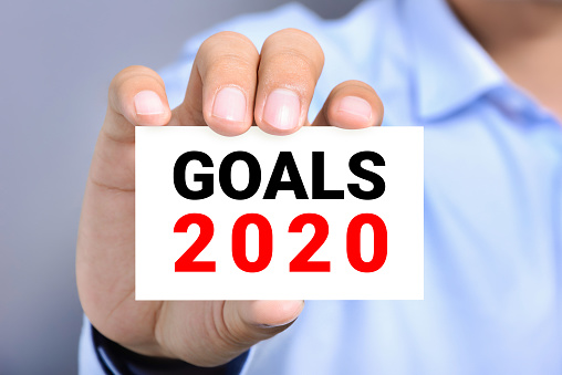Hand of businessman showing card with text GOALS 2020