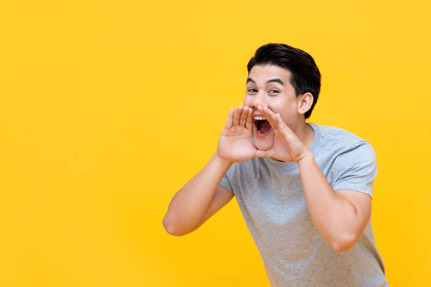 istock Young happy asian man yelling with hands cup around mouth 1191133302