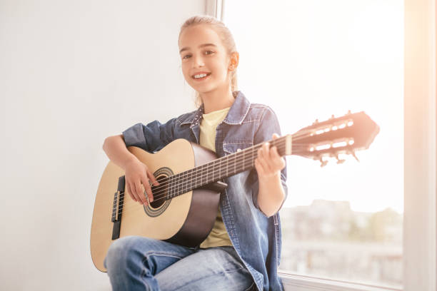 istock Confident girl self-learning playing guitar at home 1191133438