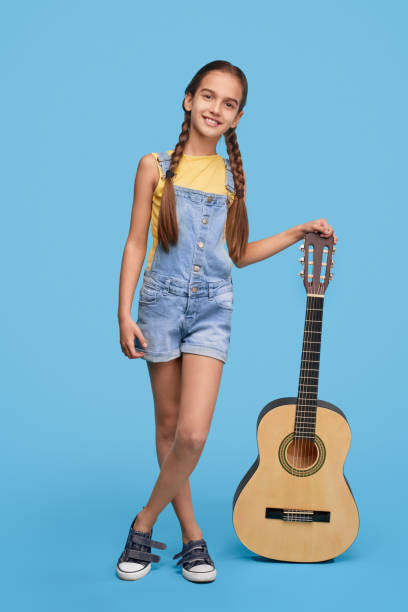 Little guitarist leaning on instrument and smiling